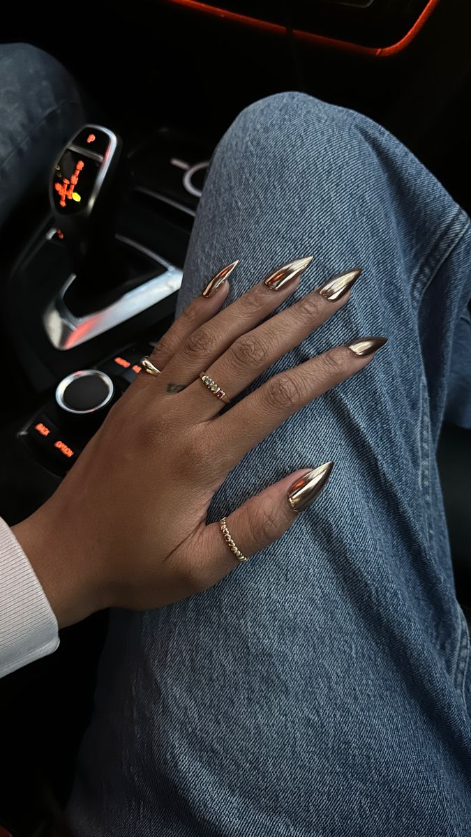 Sleek Metallic Nail Design: A Bold Statement with Elegant Elongated Shapes and Delicate Jewelry Accents.