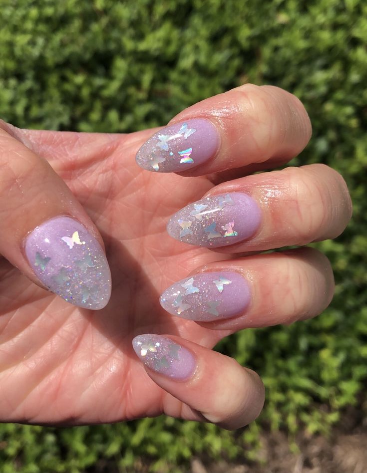 Enchanting Glittery Butterfly Nail Design: Soft Lavender Base with Translucent Tips and Shimmering Motifs.