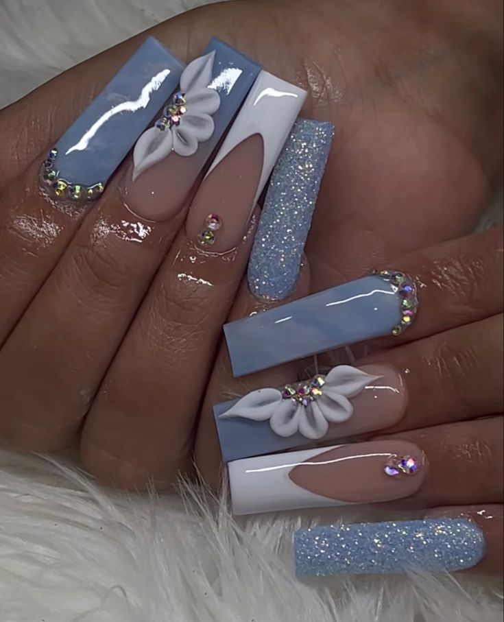 Elegant Nail Design with Soft Blue and Nude Shades, Floral Accents, and Sparkling Rhinestones.