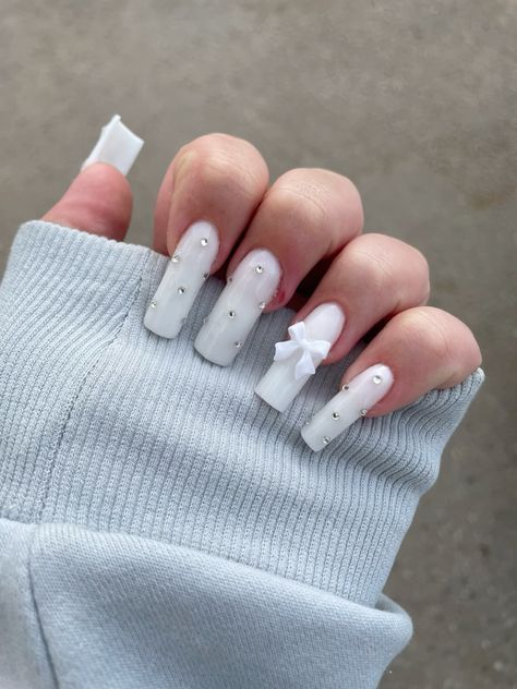 Chic White Nail Design with Rhinestones and Bow for Special Occasions.