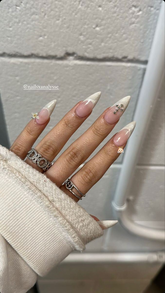 Chic Stiletto Nails: Nude Base with Classic White Tips and Glamorous Embellishments.