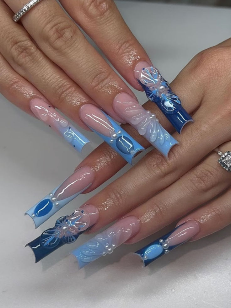 Sophisticated Gradient Blue and Pink Nail Design with Floral Patterns and Pearl Accents.