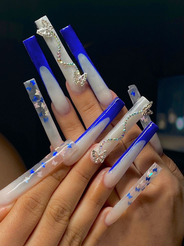 Glamorous Elongated Acrylic Nail Design with Glossy Blue and White, Rhinestone Accents, and Holographic Star Patterns.