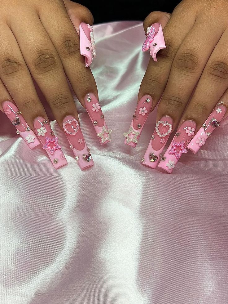 Whimsical Pink Nail Design with Floral Patterns and Sparkling Gems.