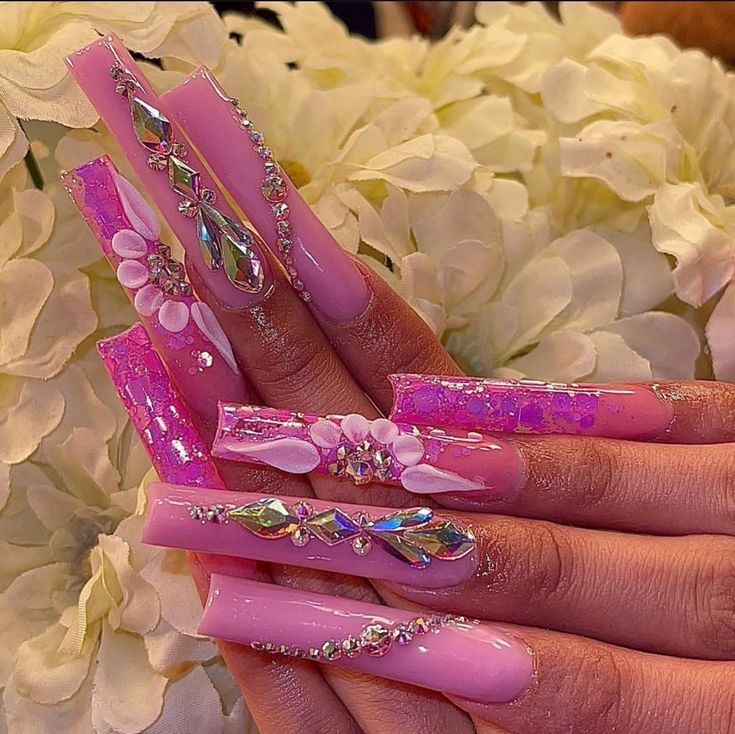 Glamorous Long Pink Acrylic Nails with Rhinestones, Pearls, and Floral Accents.