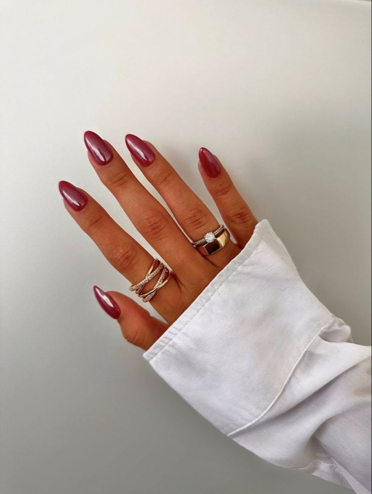 Chic Deep Burgundy Almond Nails Complimented by Silver Rings for Modern Elegance.