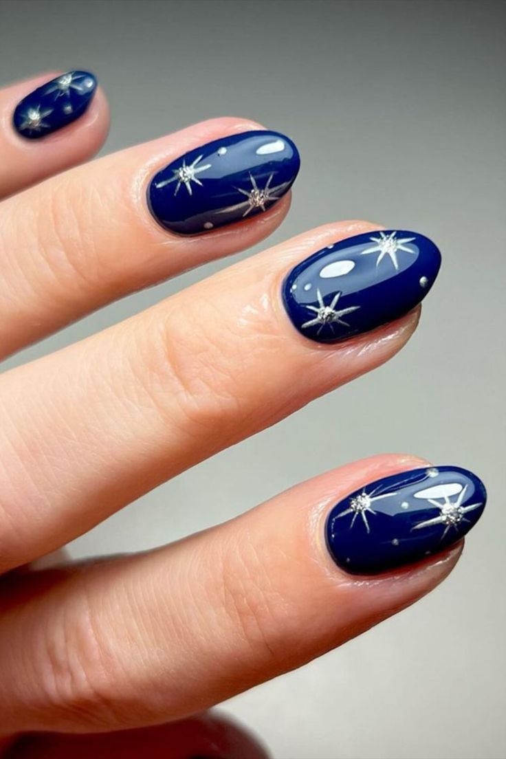 Elegant Navy Blue Nail Design with Intricate Silver Starburst Patterns.