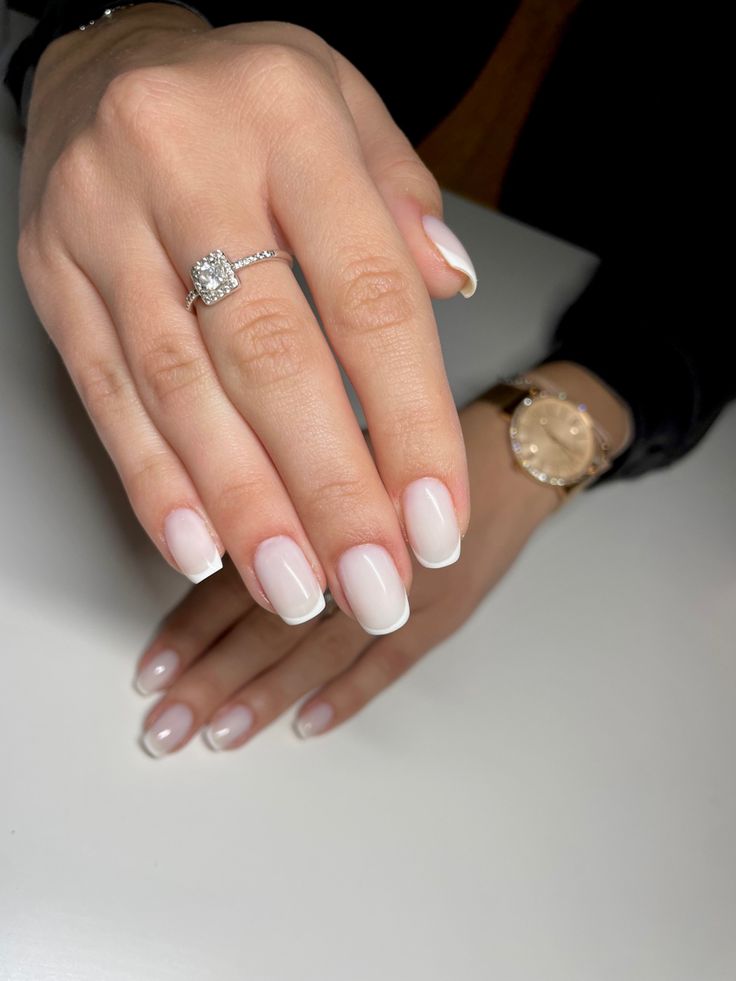 Sophisticated French Manicure with Soft Pink Base and White Tips, Enhanced by Stylish Accessories.