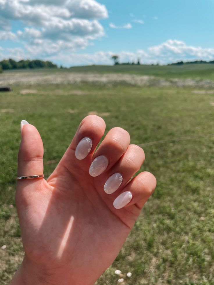 Elegant Oval Nail Design with Translucent Finish and Gem Accents for a Modern, Feminine Touch.