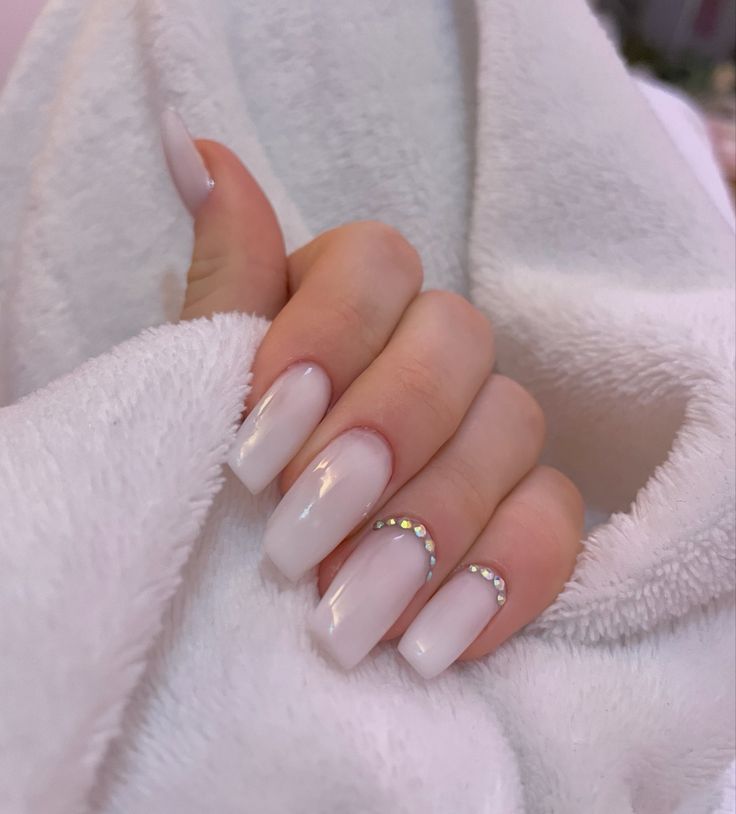 Chic White Ombre Nail Design with Glossy Finish and Elegant Rhinestone Accents.