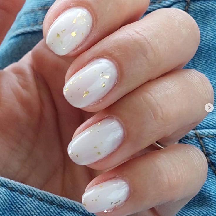 Chic Glossy White Nail Art with Delicate Gold Flakes for Versatile Glamour.