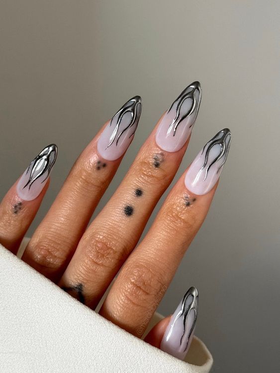 Edgy Stiletto Nail Design with Nude Base and Bold Black Flame Accents.