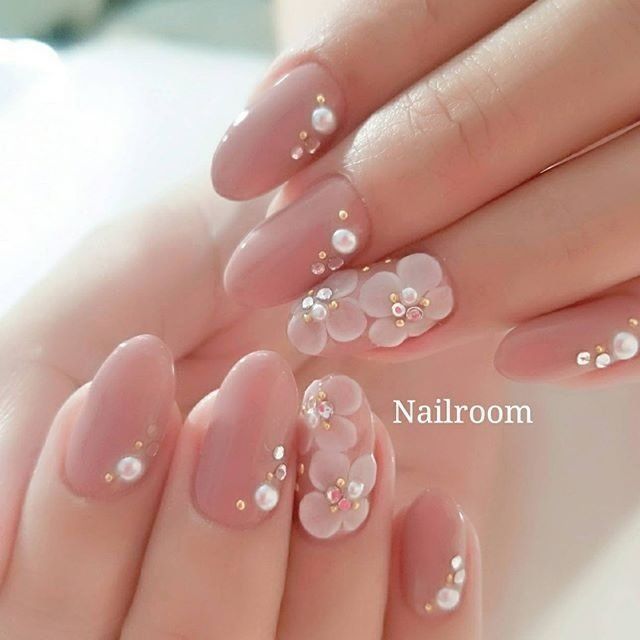 Elegant Nude Nail Design with Floral Accents and Pearl Embellishments.