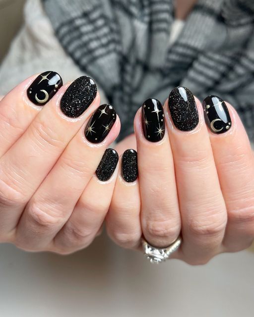 Cosmic Elegance: Glittery Black Nail Design with Celestial Motifs and Shimmering Accents