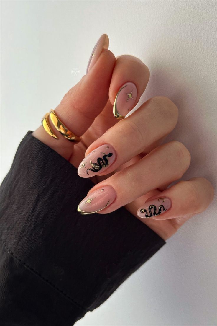 Chic Nude Nail Design with Intricate Black Snake Motifs and Glamorous Gold Accents.