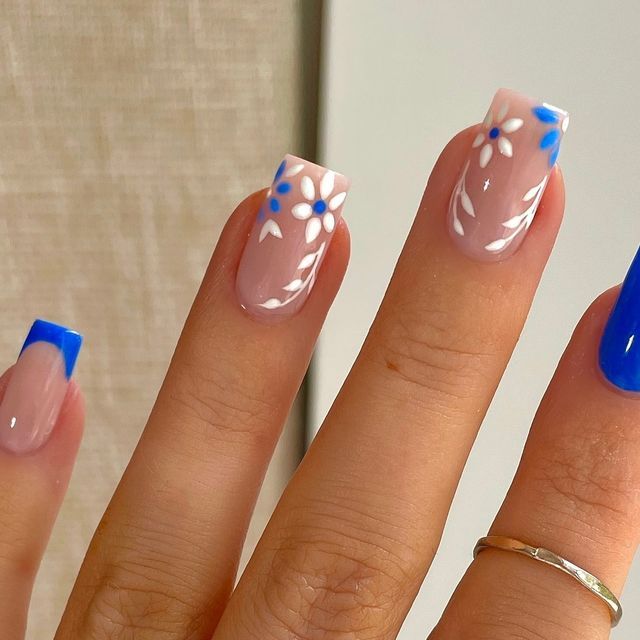 Charming Floral Nail Art with Elegant Nude Tones and Vibrant Blue Accents