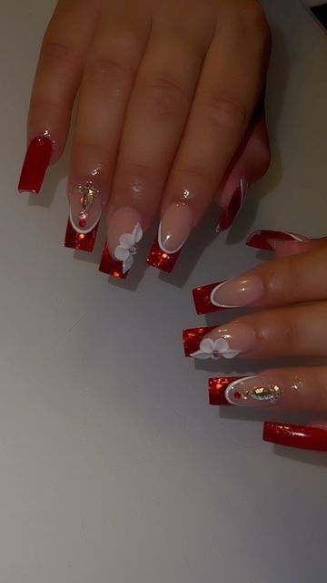 Festive and Elegant Nail Design: Vibrant Reds, Soft Nudes, Glitter Accents, and Floral Embellishments.