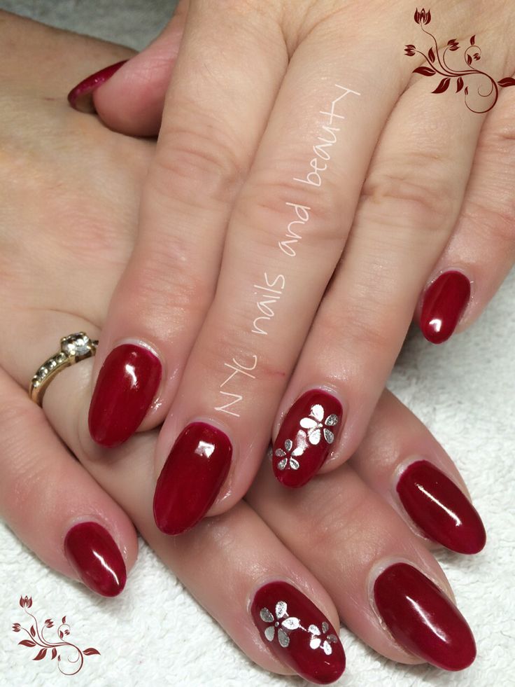 Sophisticated Oval Red Manicure with Delicate Silver Flower Accents.