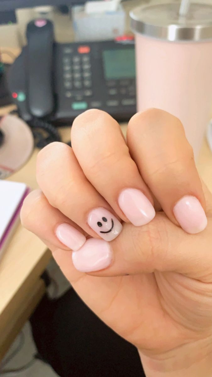 Charming Pink Nail Design with Playful Smiley Face Accent for a Trendy, Whimsical Look.