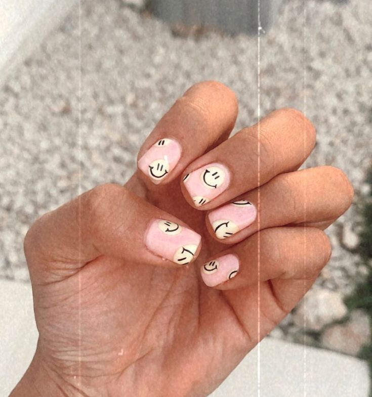 Whimsical Soft Pink Nail Design with Cheerful Smiley Faces for a Joyful Aesthetic.