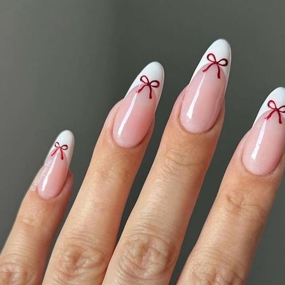 Chic Almond-Shaped Nails: Soft Pink Base with Classic White Tips and Playful Red Bow Accents.