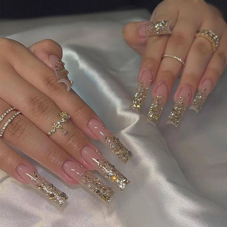 Luxurious Acrylic Nail Design with Gold Embellishments and Sparkling Details.