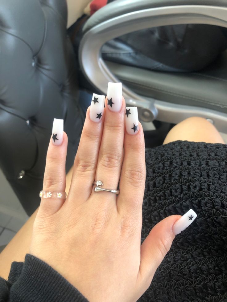 Chic White and Black Star Acrylic Nails with Elegant Jewelry Accents.