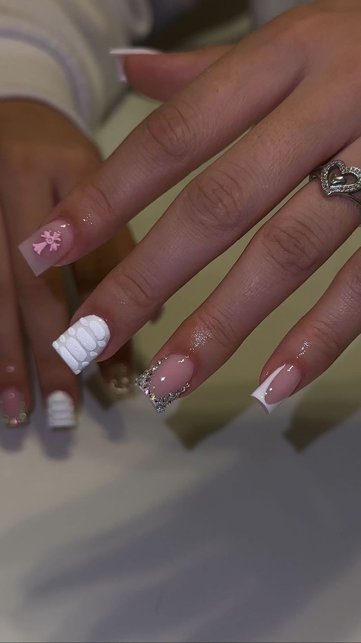 Elegant Pink and White Nail Design with Textured Details and Rhinestone Embellishments.