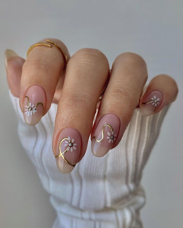 Sophisticated Nude Nail Design with Delicate Flower Embellishments and Artistic Gold Accents.