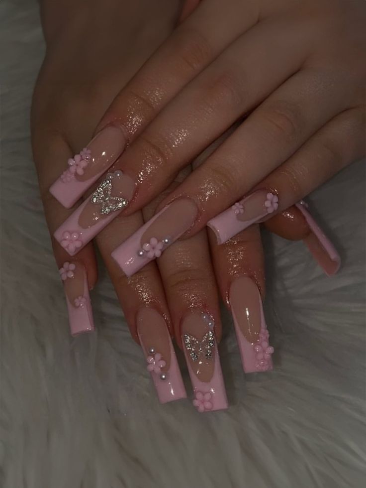 Whimsical Long Glossy Pink Acrylic Nail Design with Floral and Butterfly Embellishments.