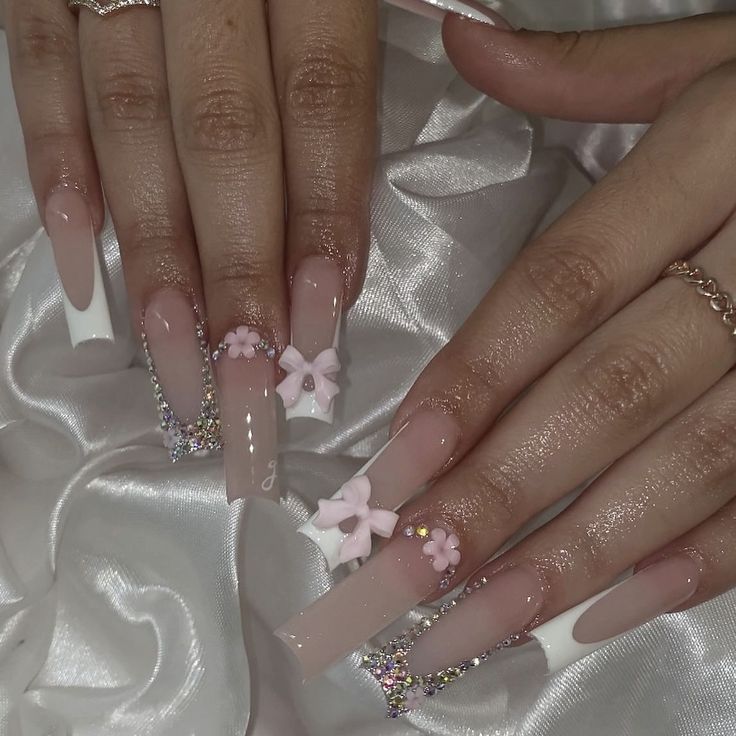 Sophisticated Nail Design: Nude Base with Floral Accents, Bows, and Rhinestone Detailing.