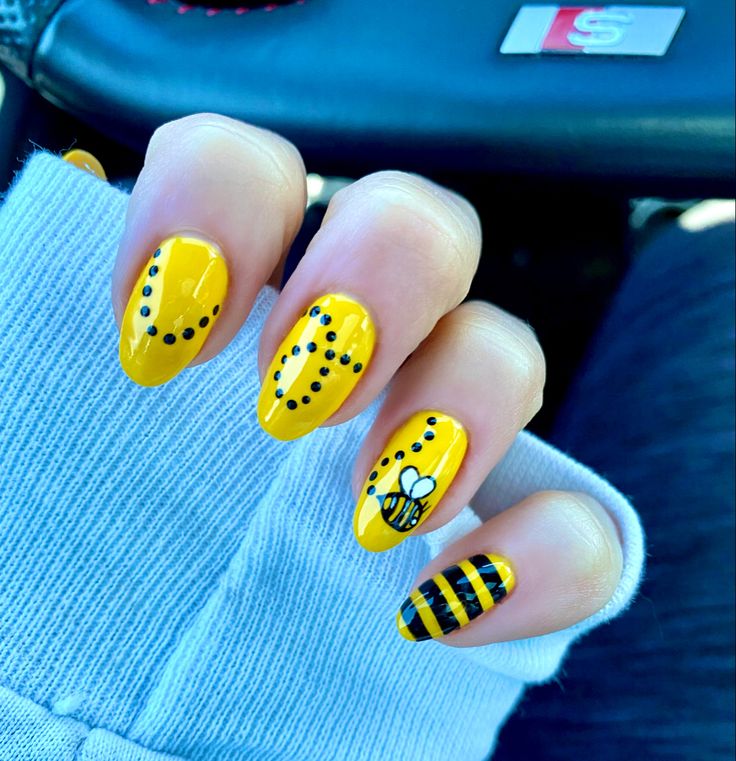 Cheerful Summer Nail Design: Vibrant Yellow with Polka Dots, Bee Illustration, and Bold Stripes.