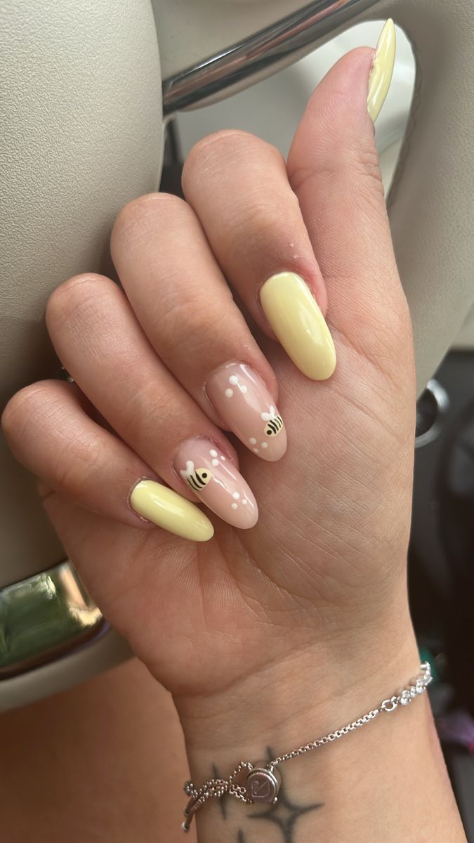 Whimsical Nail Design: Soft Yellow and Pastel Pink with Playful Bee Motifs and Glossy Finish.