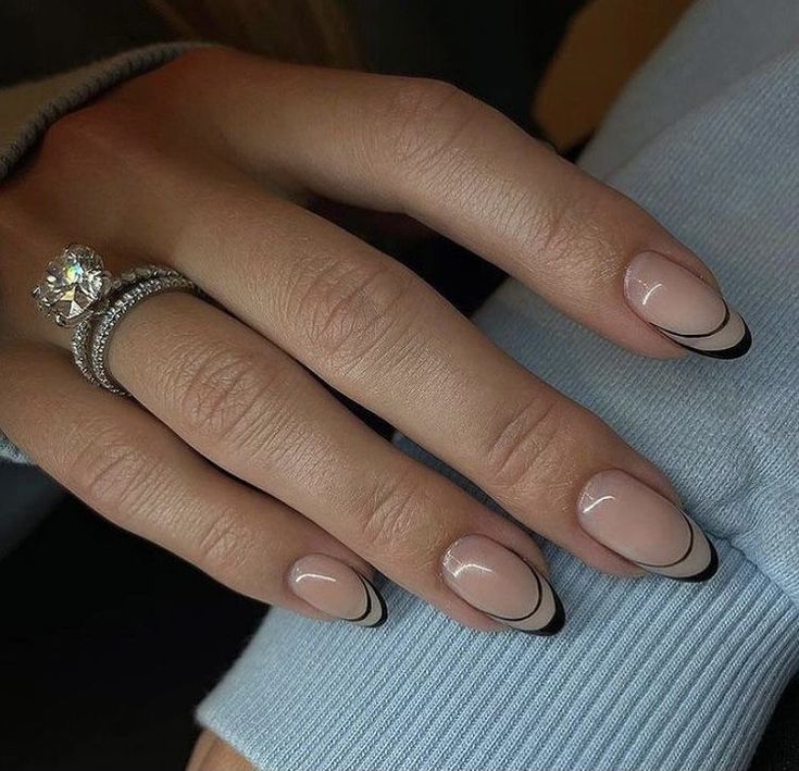 Chic Almond-Shaped Nails: Nude Base with Glossy Black Tips and Sparkling Ring Accents.