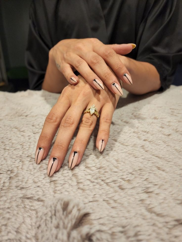 Sophisticated Nail Art: Pointed Tips with Nude and Black Accents.