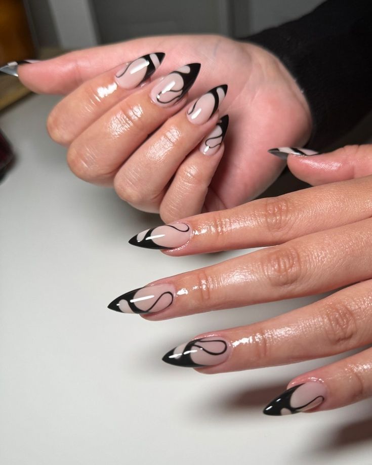 Sophisticated Almond-Shaped Nail Design in Nude and Black with Glossy Finish and Artistic Details.