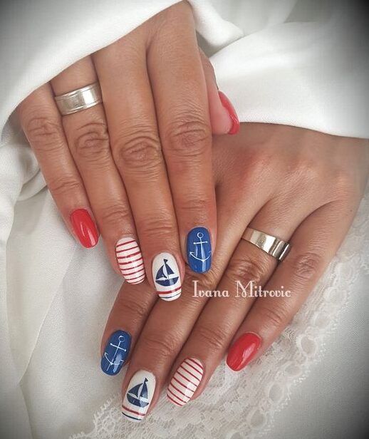 Nautical Nail Design: Vibrant Red and Deep Blue with Fun Striped Patterns and Anchor Motifs for Summer.