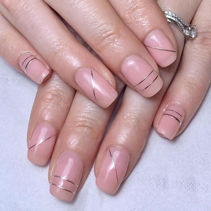 Chic Minimalist Nail Design: Soft Pink Base with Delicate Metallic Lines and Geometric Patterns.