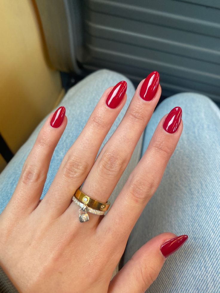 Elegant Red Almond Nails with Glossy Finish and Sophisticated Rings.