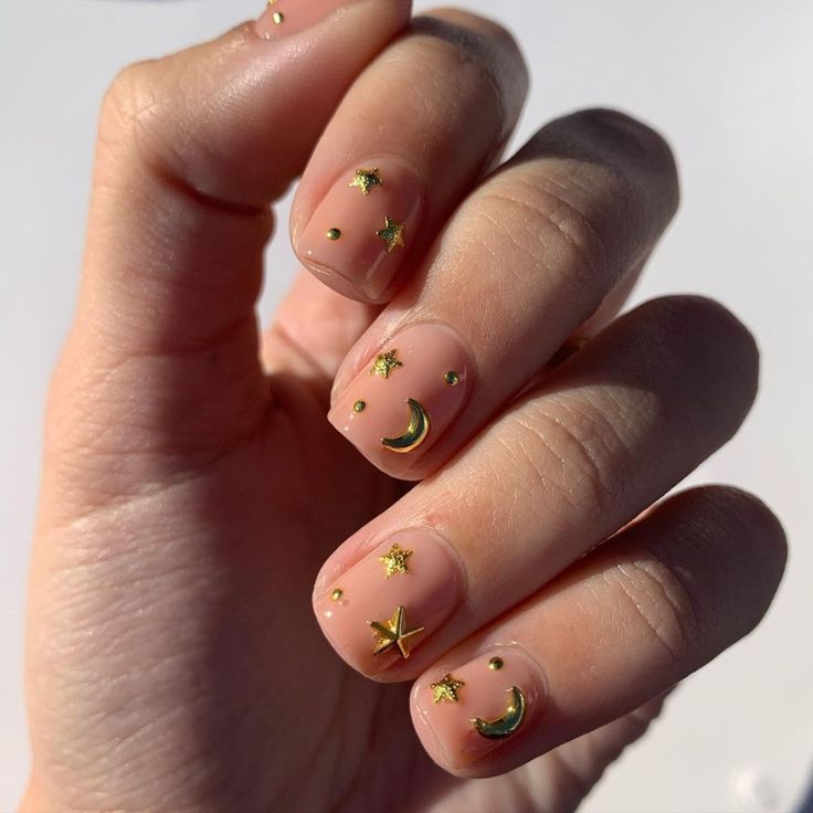 Whimsical Celestial Nail Design with Gold Accents on a Nude Base.