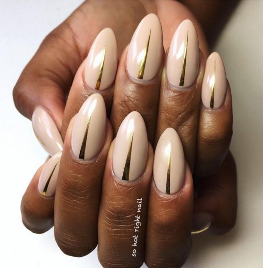 Chic Almond-Shaped Nude Nails with Glamorous Gold Metallic Stripes.