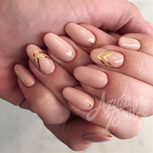 Chic Almond-Shaped Nails with Soft Nude Base and Delicate Gold Chevron Accents.