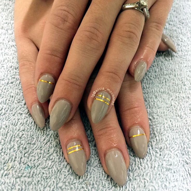 Chic Taupe Almond-Shaped Nails with Subtle Gold Stripes for a Modern Look.