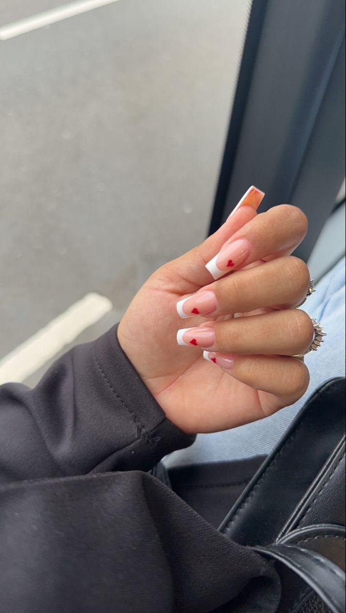 Charming French Manicure with Soft Pink Base and Whimsical Red Hearts.