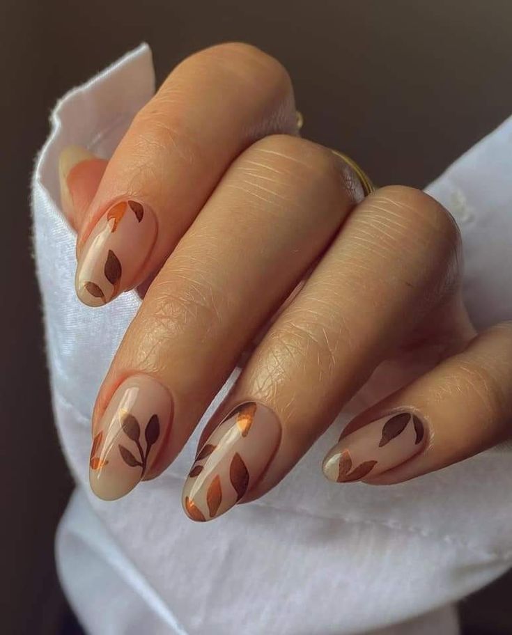 Sophisticated Autumn-Inspired Nail Design with Transparent Base and Leaf Patterns in Earthy Tones.