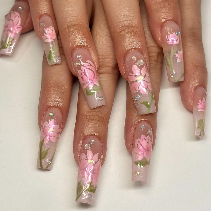 Elegant Floral Nail Design: Soft Pink Blooms and Sparkling Gem Accents on Clear Elongated Nails