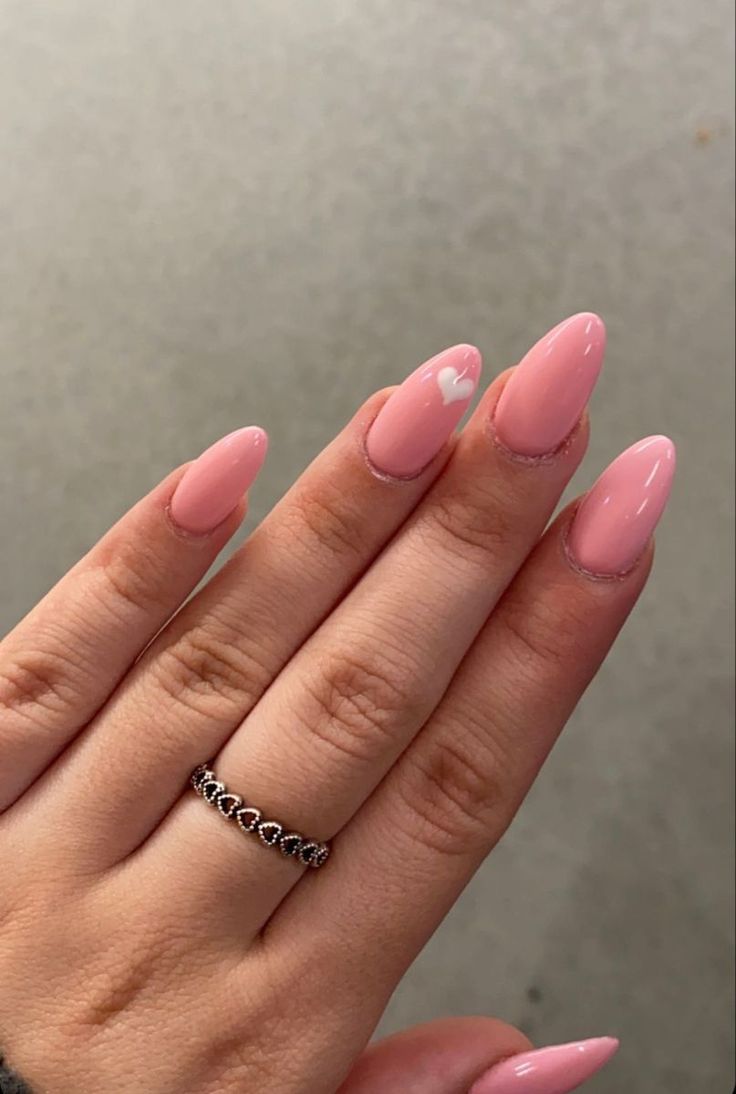 Chic Almond-Shaped Pink Nails with Heart Accent and Dainty Ring.