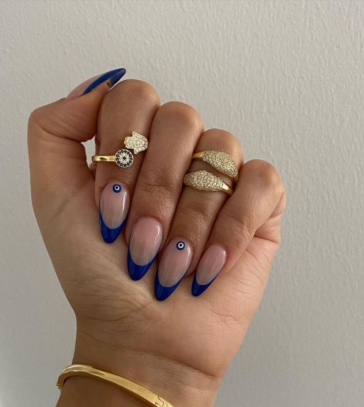 Sophisticated Nail Design: Blue French Tips with Evil Eye Accents and Chic Gold Rings