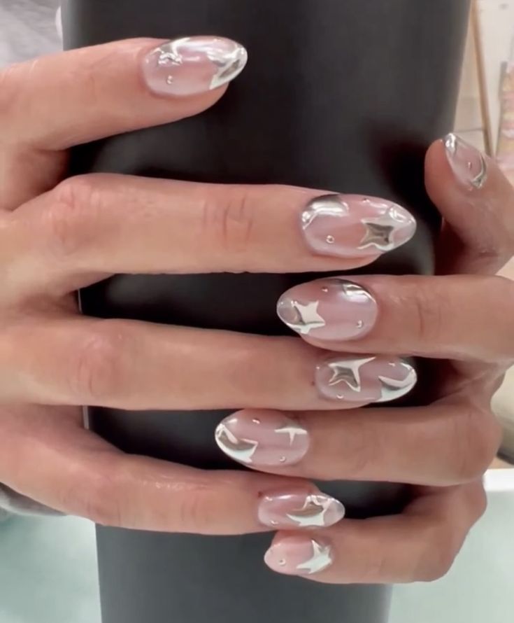 Chic Translucent Nail Design with Silver Star Accents and Playful Metallic Elements.