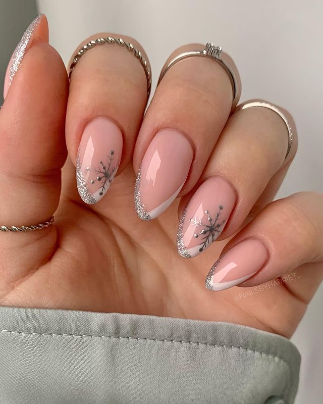 Chic Winter Nail Design: Soft Pink Base with Delicate Silver Glitter Tips and Whimsical Snowflake Motifs.